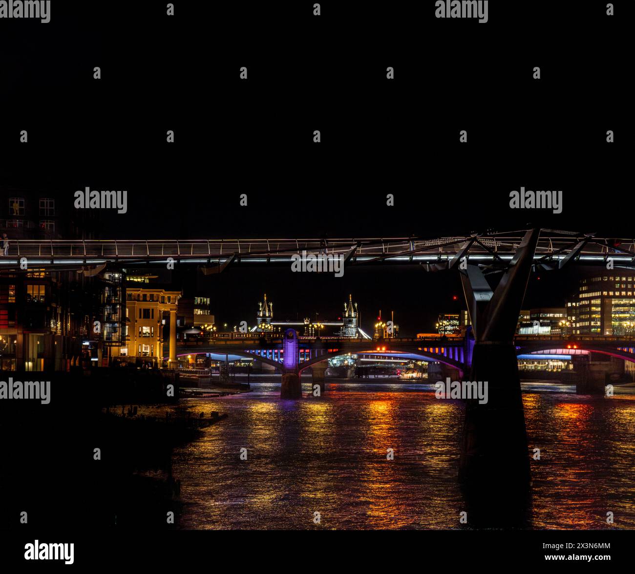 Frontalblick von der Themse auf die Millennium Bridge, Blackfriars Bridge und die Tower Bridge bei Nacht, deren Lichter im Rive reflektiert werden Stockfoto