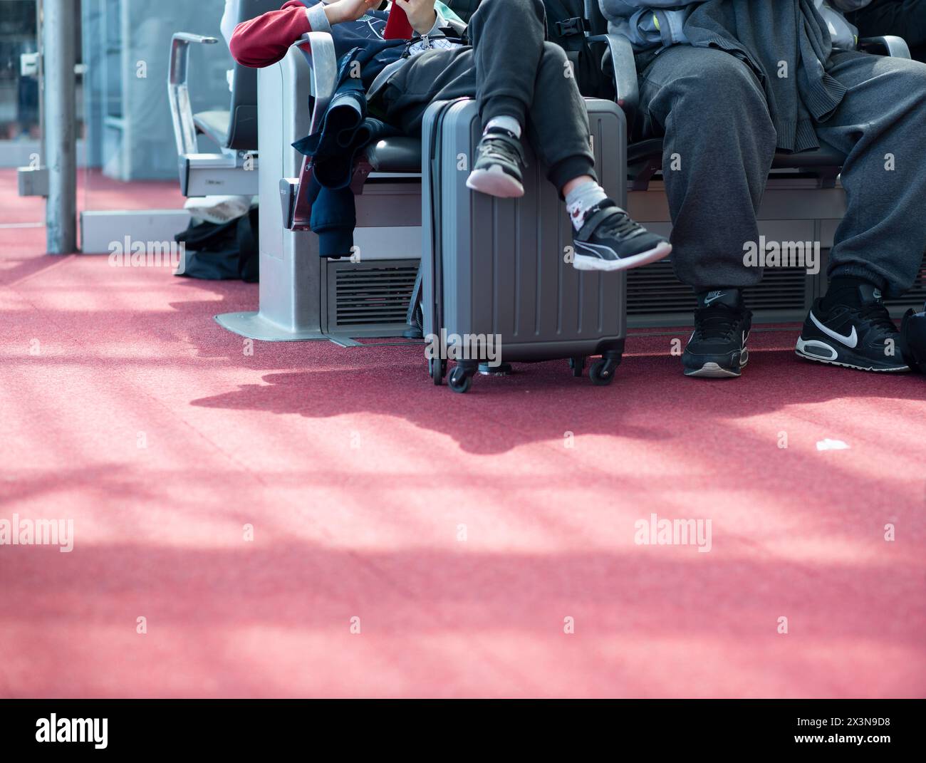 Angabe der Passagiere mit Koffern, die in einem Terminal eines Flughafens in Paris, Frankreich, sitzen, während sie auf ihren Flug warten Stockfoto