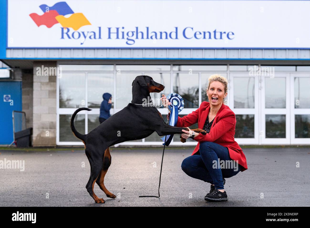 Ein Dobermann und sein Führer feiern mit einer Rosette auf der Hundeshow des Scottish Kennel Club im Royal Highland Centre, Edinburgh, Schottland, UK Stockfoto