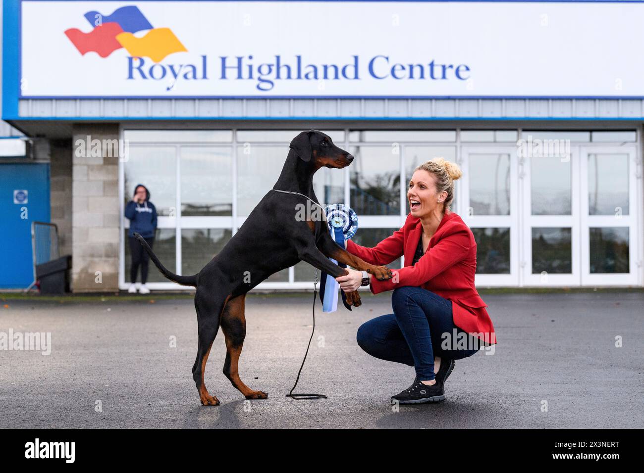Ein Dobermann und sein Führer feiern mit einer Rosette auf der Hundeshow des Scottish Kennel Club im Royal Highland Centre, Edinburgh, Schottland, UK Stockfoto