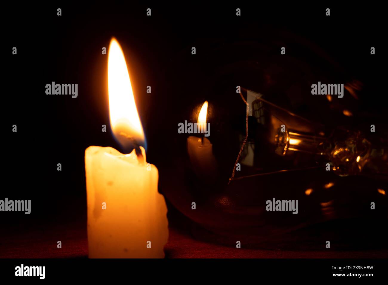 Glühlampe und Kerze im Dunkeln zu Hause, ohne Licht Stockfoto