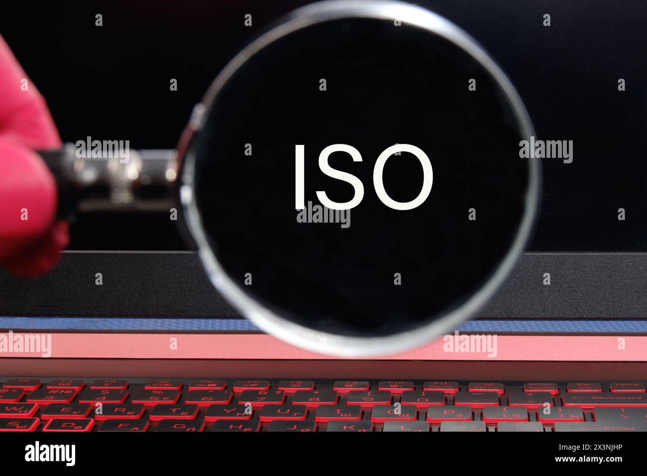 Das Konzept der ISO-Qualitätskontrollzertifizierung. Die Abkürzung ISO Text erscheint durch eine Lupe auf schwarzem Hintergrund Stockfoto