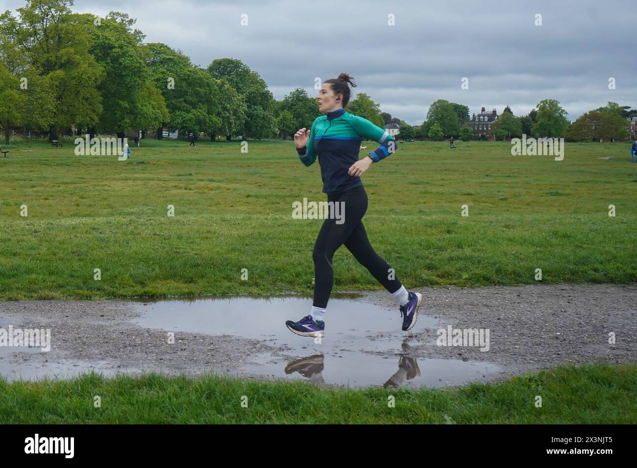 London, Großbritannien. 28. April 2024. Ein Jogger läuft über große Wasserpfützen in Wimbledon Common im Südwesten Londons, das bei anhaltendem feuchten Wetter unter Wasser liegt. Credit: amer ghazzal/Alamy Live News Stockfoto