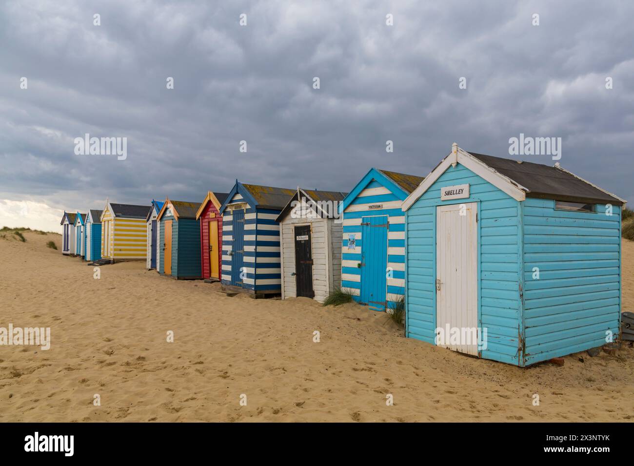 Alte Strandhütten, die nach berühmten Menschen und Monarchen benannt sind, mit Sanddünen am Southwold Denes Beach, Southwold, Suffolk, Großbritannien im April Stockfoto