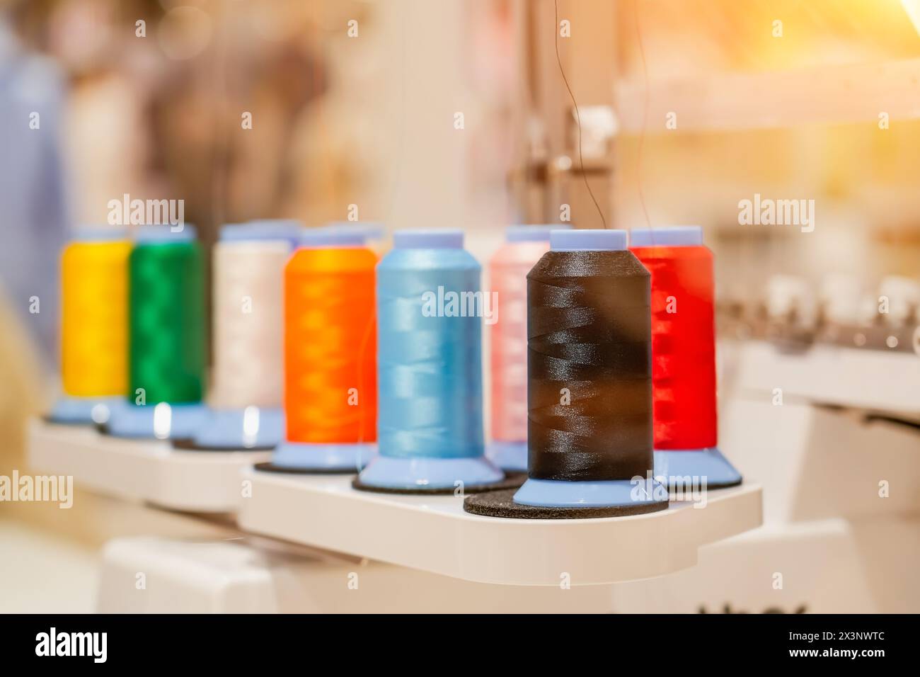 Spulen aus farbigem Faden, die auf einer automatischen digitalen Nähmaschine installiert sind. Stockfoto