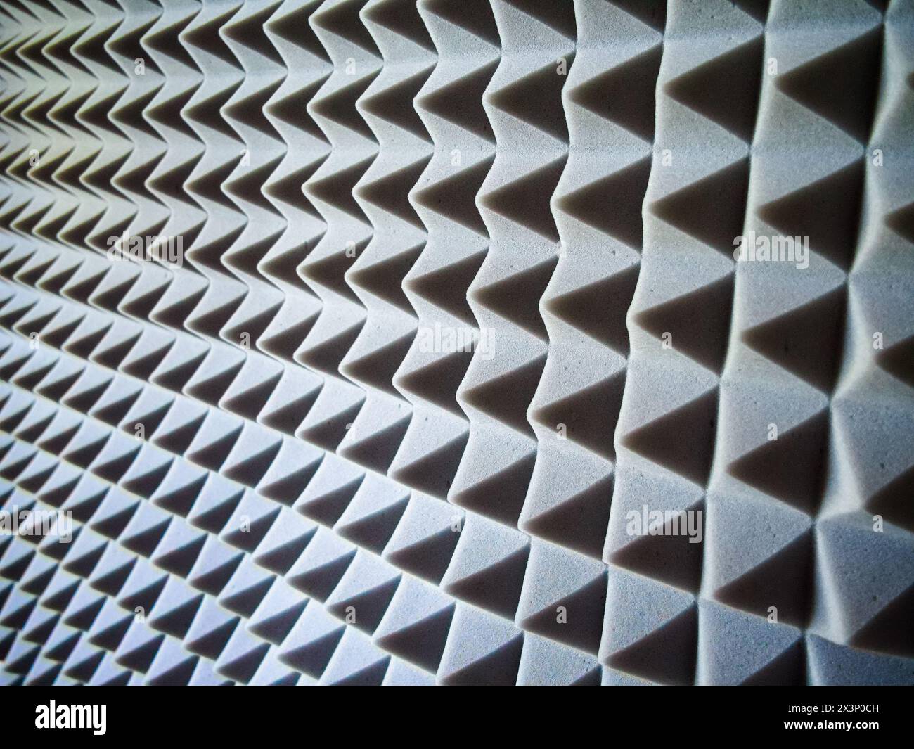 Akustische Schaumstoffplatten. Graue Paneele mit Pyramidenmuster für Schalldämmung und Geräuschreduzierung. Stockfoto