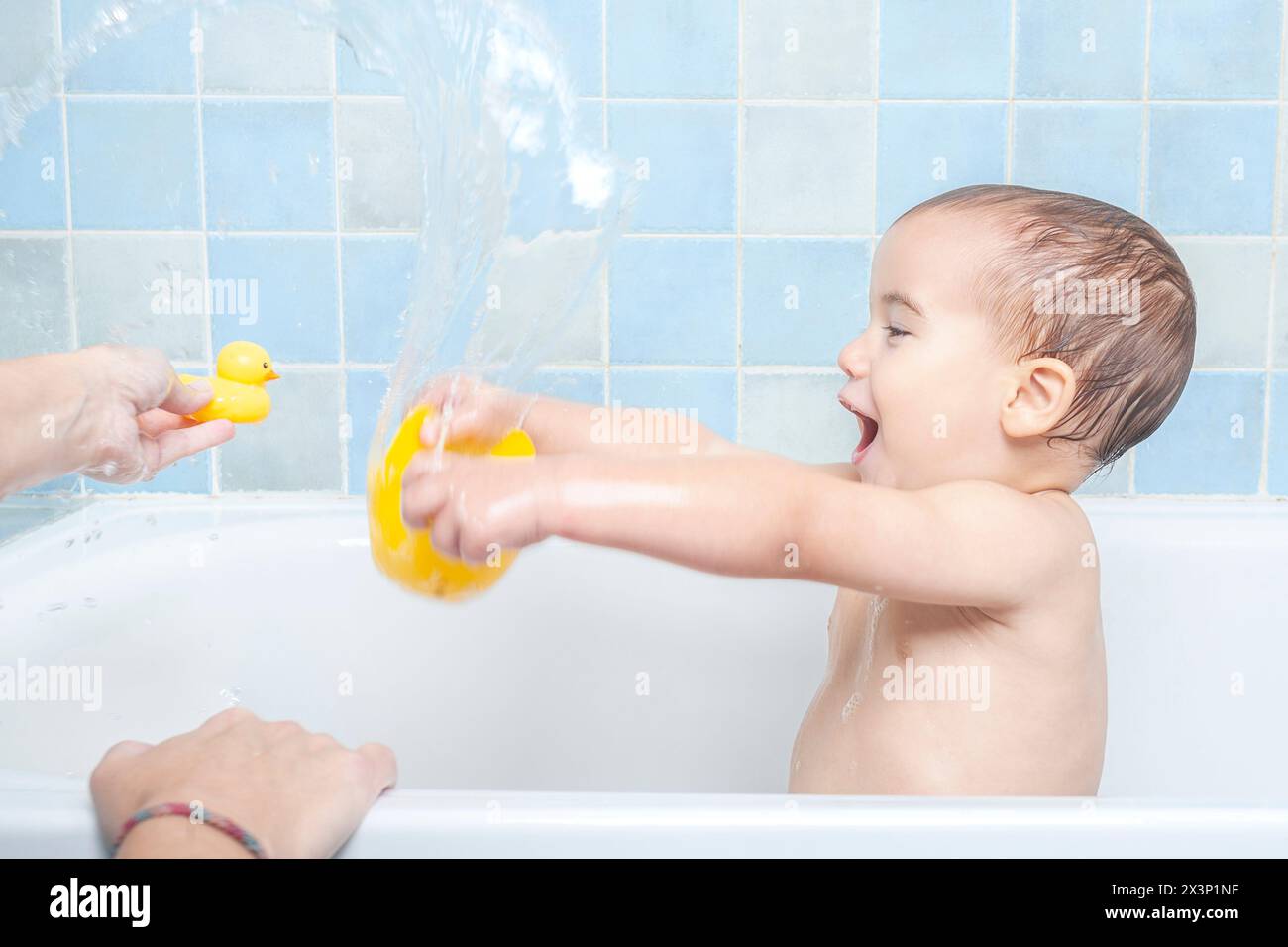 Das Kind spritzt Wasser in die Badewanne Stockfoto