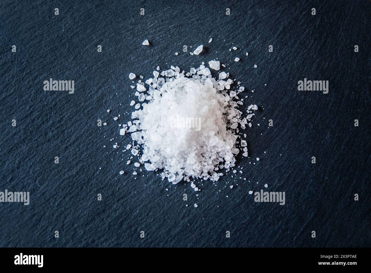 Weiße Salzkristalle auf schwarzem Hintergrund. Salzkristalle zum Kochen der Speisen. Stockfoto