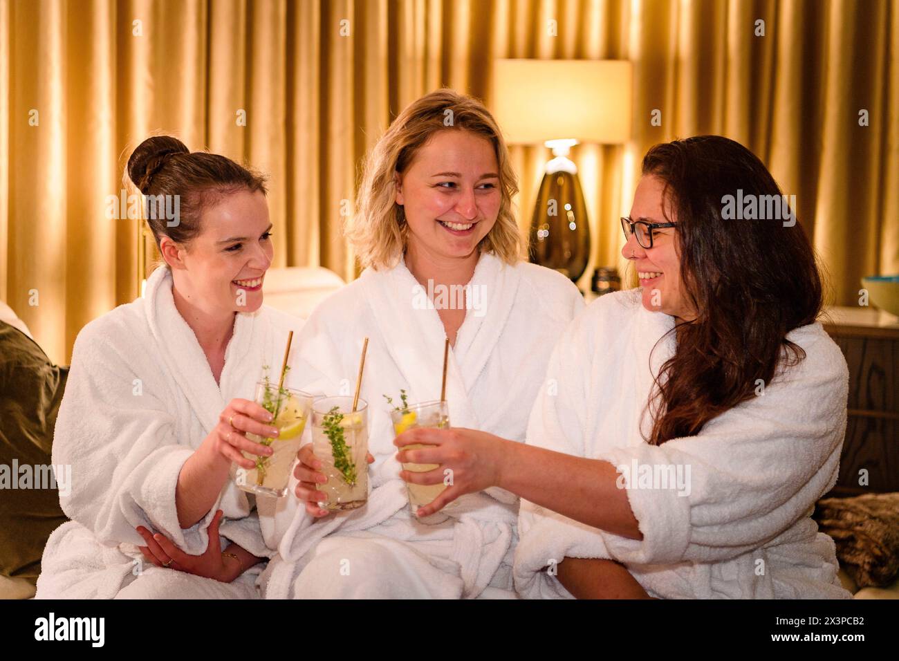 Frauen in Gewändern stoßen mit Getränken bei der Spa-Eröffnungsfeier im Waldorf Astoria Edinburgh - The Caledonian, Edinburgh, Schottland, UK an Stockfoto