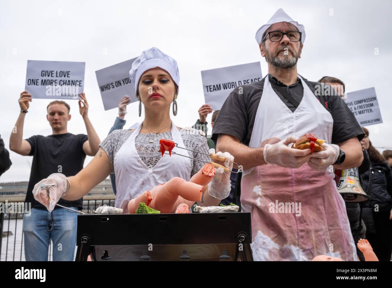 Vegane Demonstranten geben vor, menschliche Babys während der Kundgebung zu kochen. Die vegane Gruppe Radically Kind hielt eine Demonstration im Tate Modern am Südufer der Themse ab. Mit grafischen Bildern hoffen sie, Fleischesser in Veganismus zu verwandeln. Stockfoto