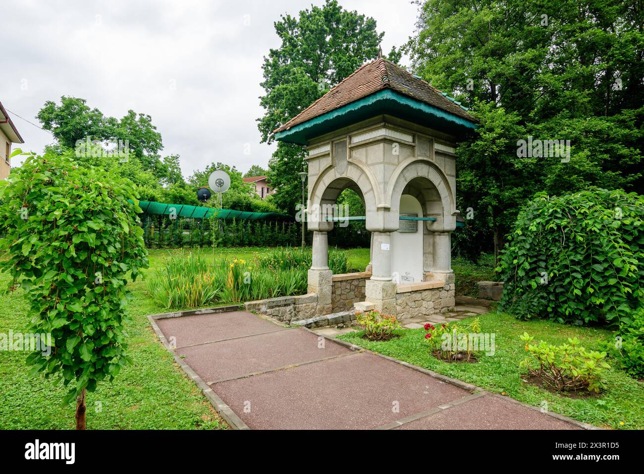 Fantana Jianu (Jianu-Brunnen) am Haupteingang zum Alexandru Buia Botanical Garden von Craiova in Dolj County, Rumänien, und große grüne Tres in einer Schönheit Stockfoto