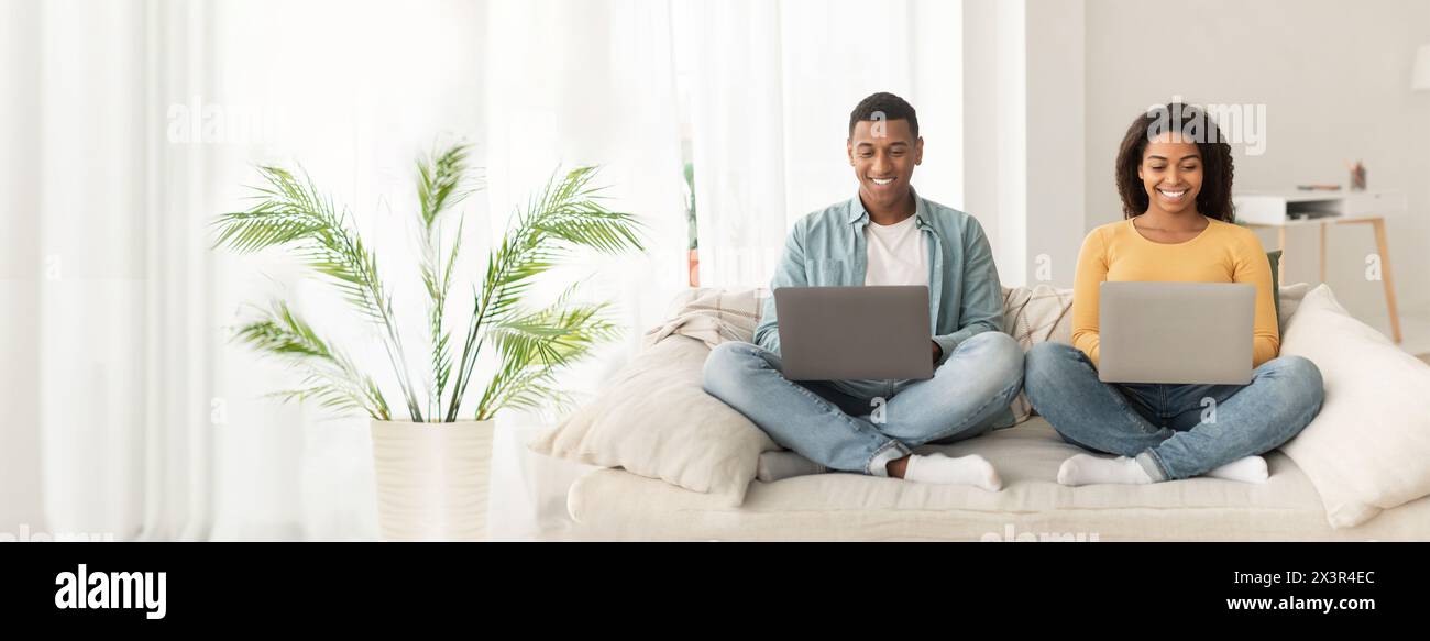 Paare auf der Couch mit Laptops zu Hause Stockfoto