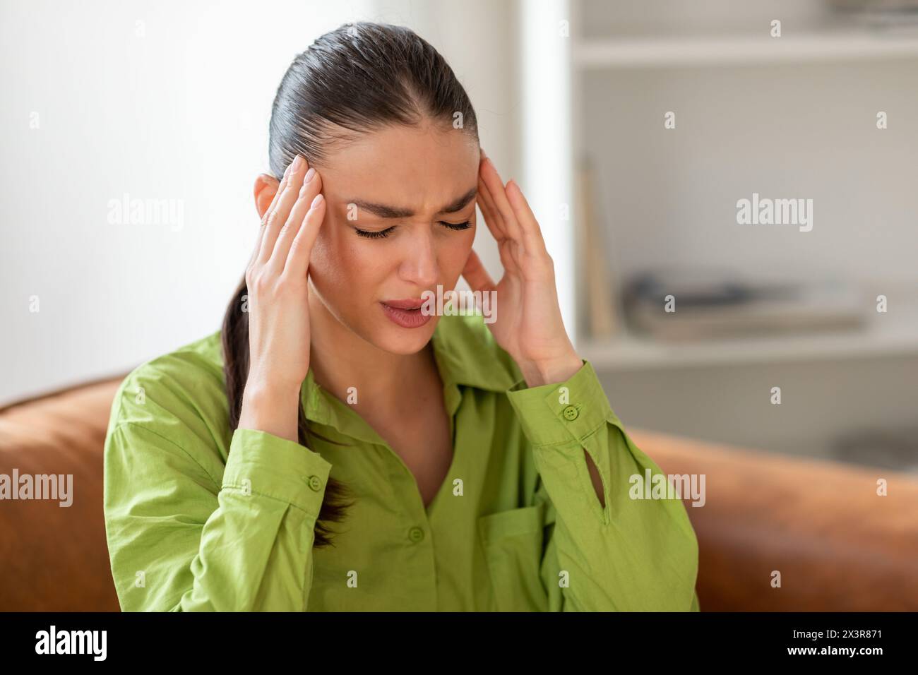 Frau, die auf der Couch sitzt und Kopf hält, Großaufnahme Stockfoto