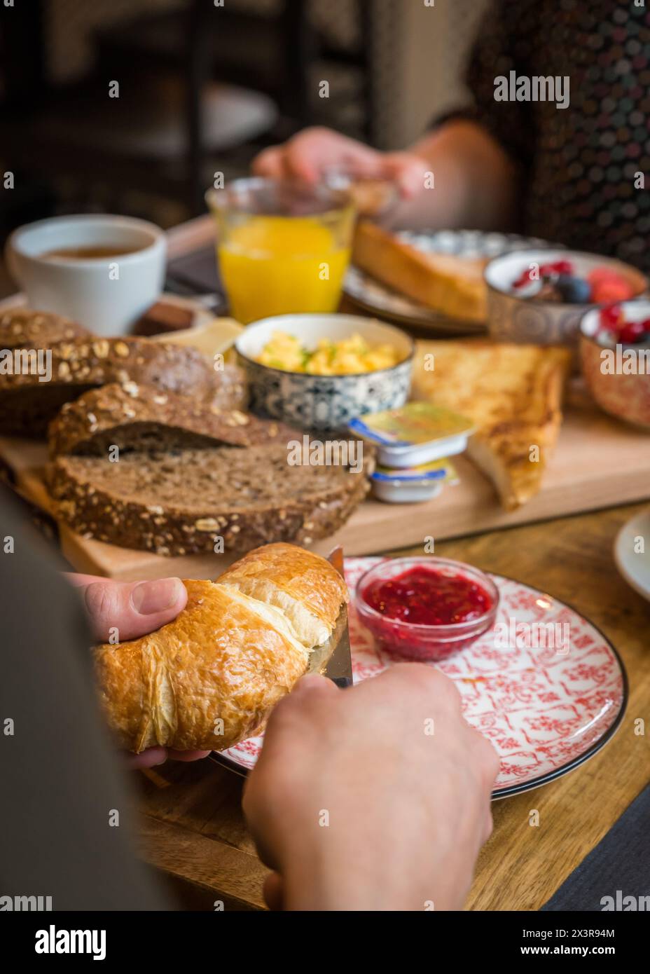 Croissants werden während des Frühstücks in Scheiben geschnitten in einem Bäckereicafé Stockfoto