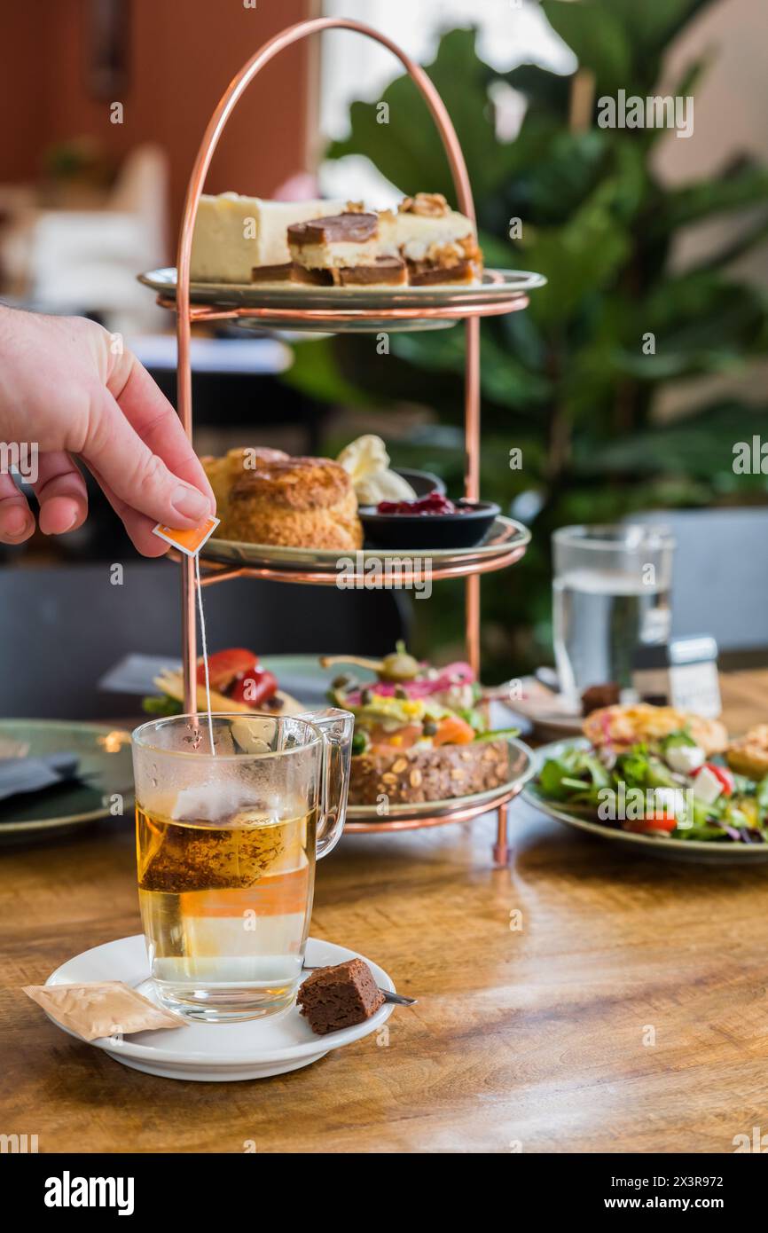 Traditioneller englischer Nachmittagstee mit einer Mischung aus süßen und herzhaften Snacks und Häppchen auf einem Tisch in einem Bäckereicafé Stockfoto