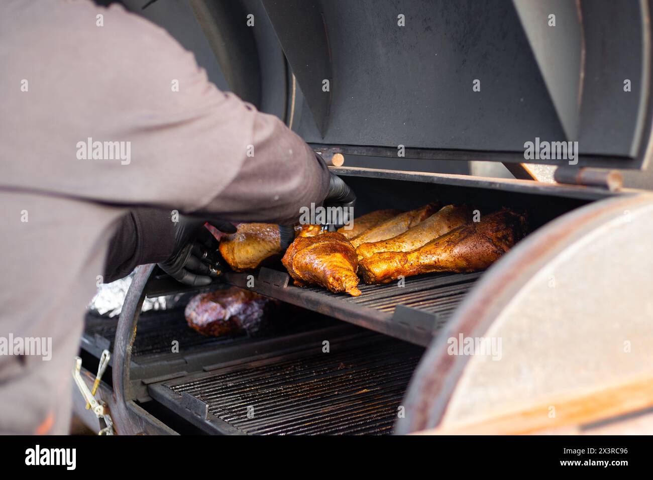 Truthahnbeine werden auf einem professionellen Grill gebacken. Der Prozess der Fleischzubereitung für ein Picknick. Stockfoto