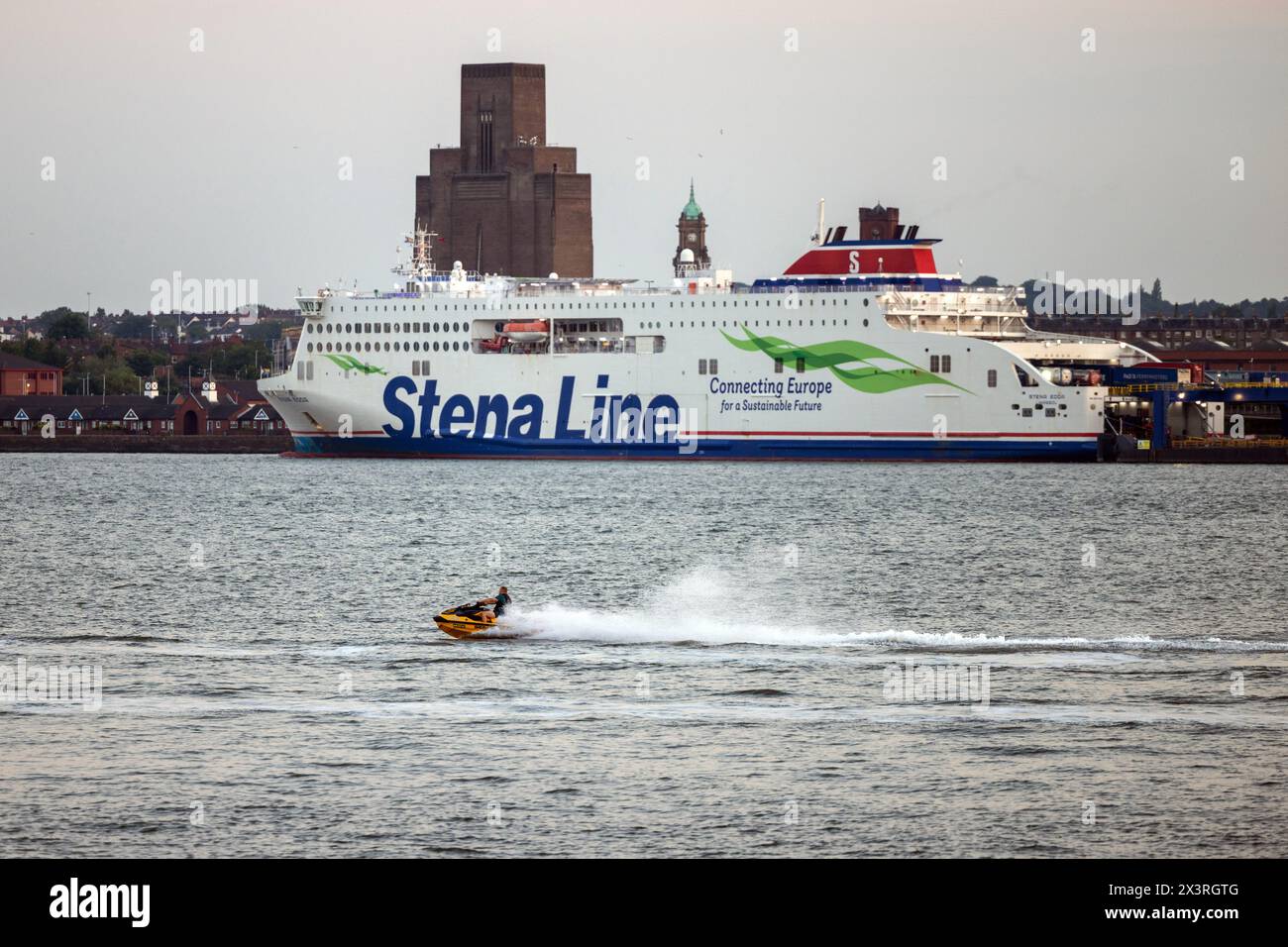 Ein Jetski-Fahrer rastet in Liverpoool den River Mersey hinauf mit der Belfast-Fähre, die an der Küste von Wirral angedockt ist Stockfoto