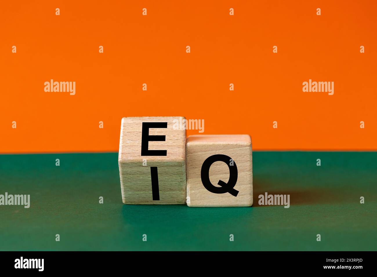 EI- oder EQ-Symbol. Ein Holzblock mit einem Wort, das sowohl das Symbol der emotionalen Intelligenz als auch den emotionalen Quotienten zeigt. Wunderschöner grüner und orangener Backgro Stockfoto