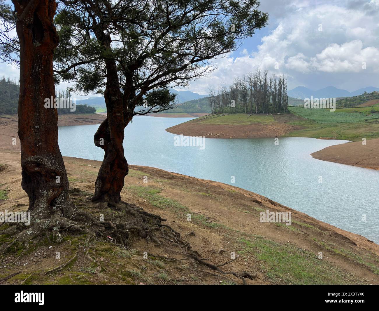 Hoch aufragende Berge, Fluss mit sichtbarer kleiner Insel, blauer und weißer Himmel, Spiegelung sichtbar im Wasser, das Geschenk der Natur von Grün überall Stockfoto