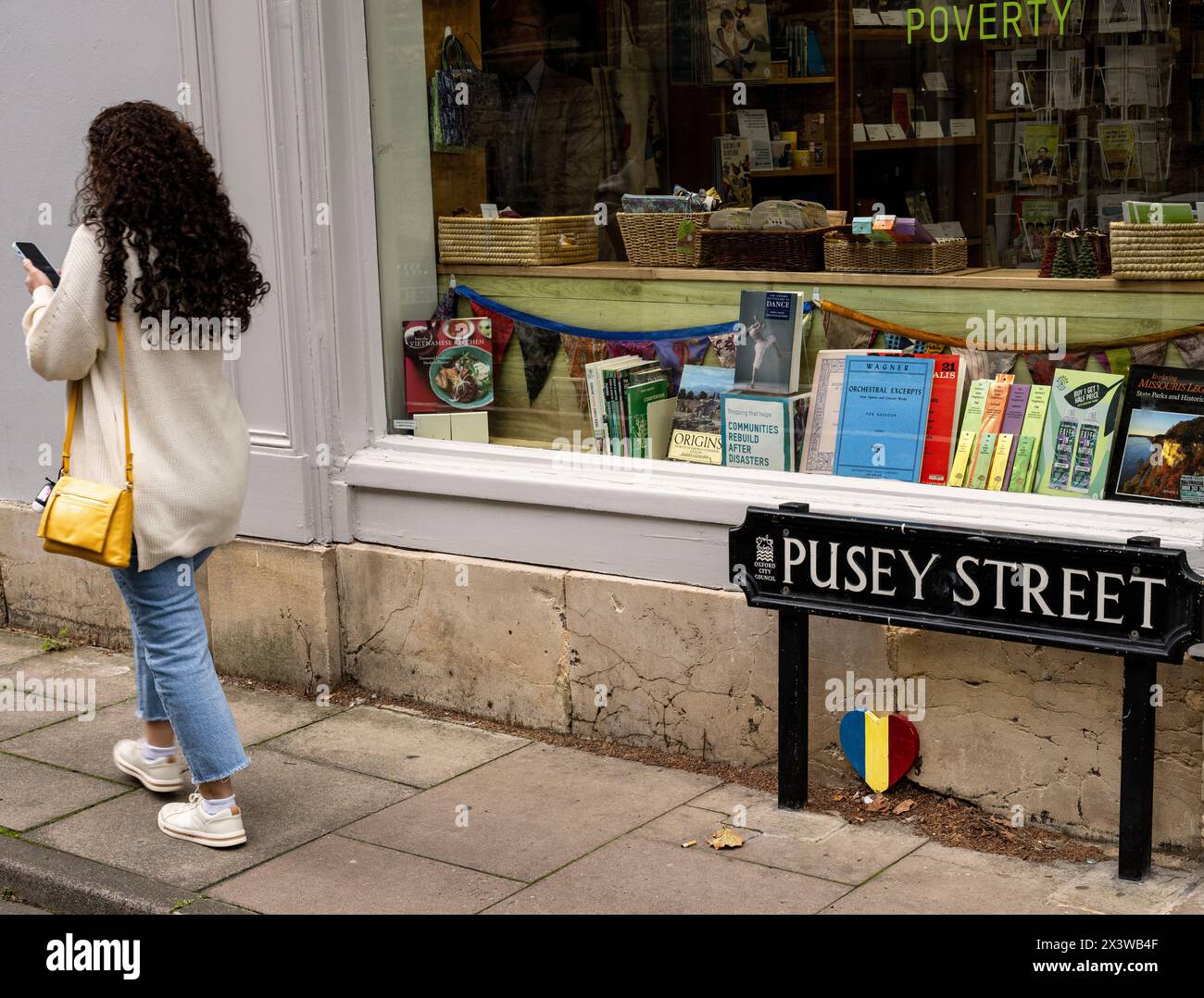 Frau in der Pusey Street, die am Oxfam Buchladen in St Giles, Oxford, vorbeiläuft Stockfoto