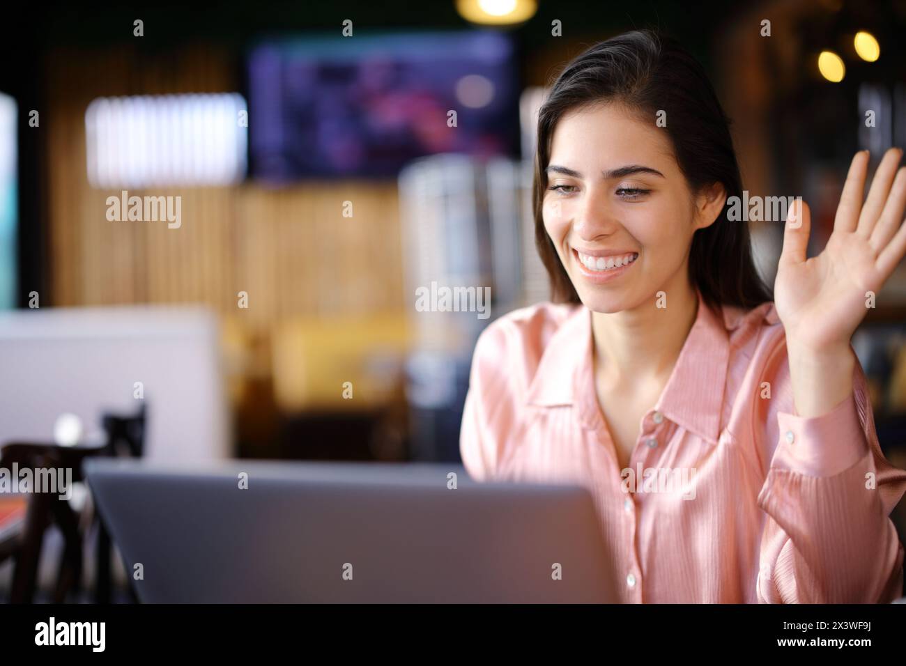 Glückliche Selbstständige, die Videoanrufe mit einem Laptop in einer Bar hatten Stockfoto