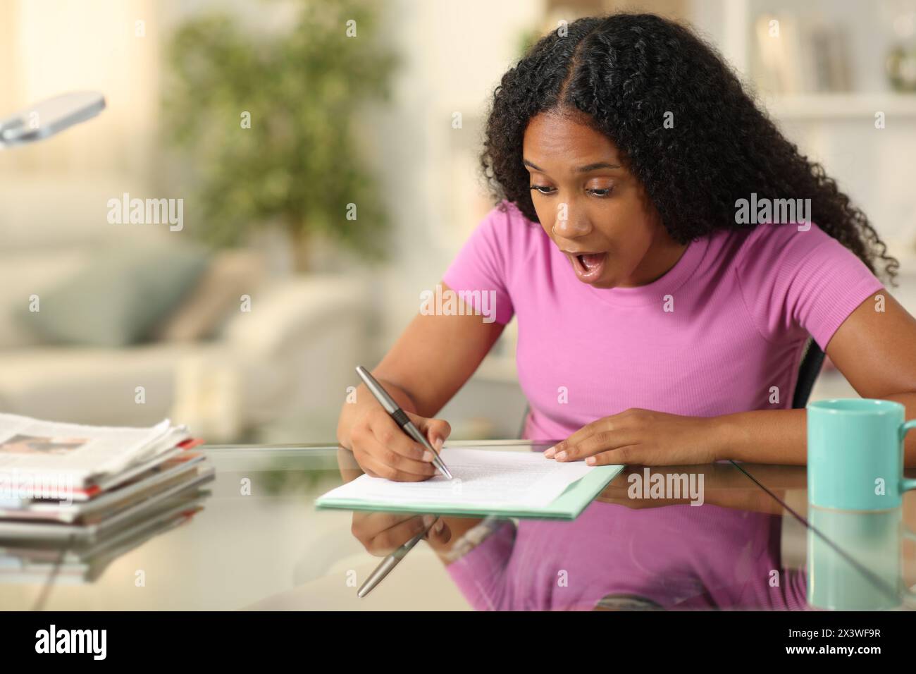 Überraschte schwarze Frau, die zu Hause einen Vertrag unterschreibt Stockfoto