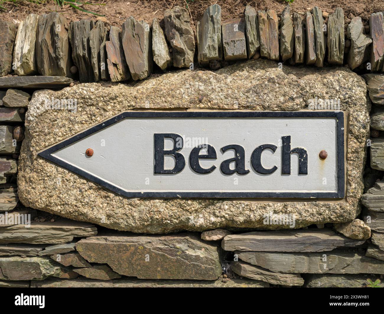 Ein metallenes „BEACH“-Schild in einer kornischen Steinmauer am Godrevy Head in Cornwall. Stockfoto