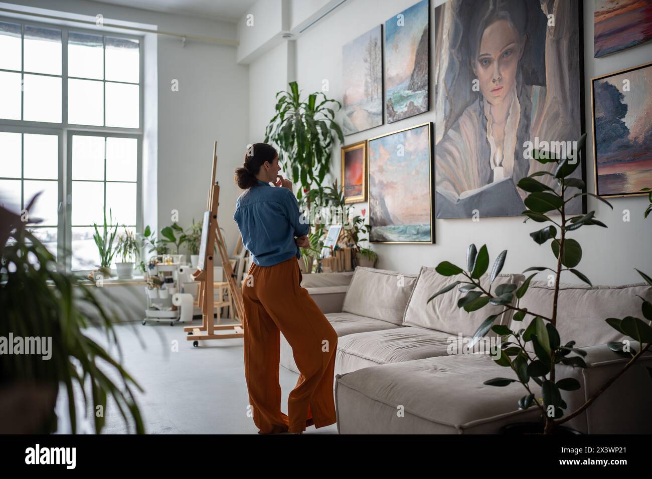 Frau, die auf Malerei schaut, Künstlerstudio. Künstlerwohnung Galerie Inneneinrichtung, Kunstwerk Hobby Stockfoto