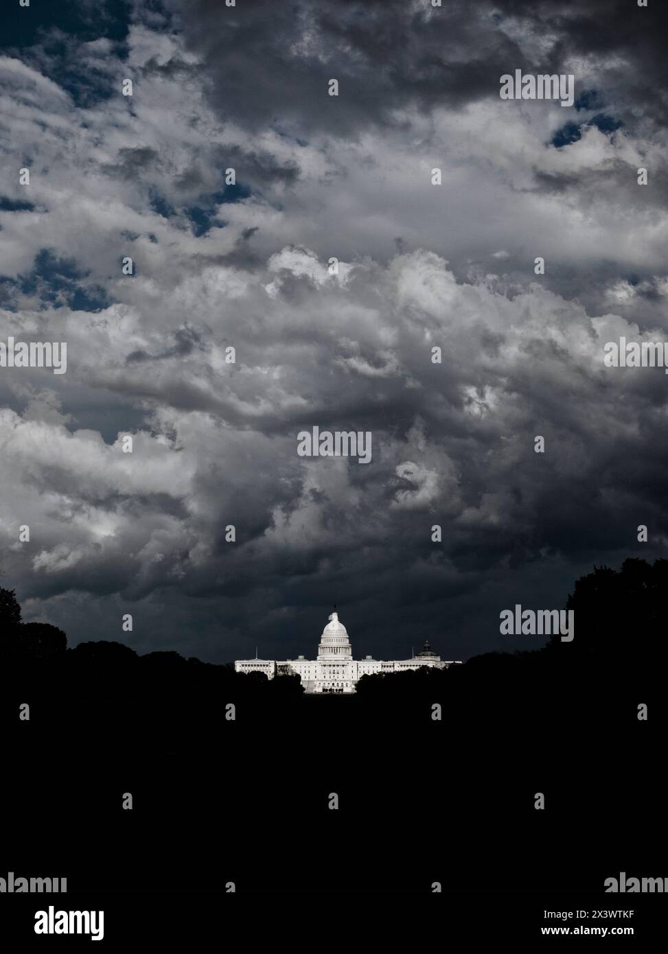 Dunkel und bedrohlich aussehende Sturmwolken wirbeln um das US Capitol Building in Washington, DC. Ein Sonnenstrahl beleuchtet das Gebäude durch die Dunkelheit Stockfoto