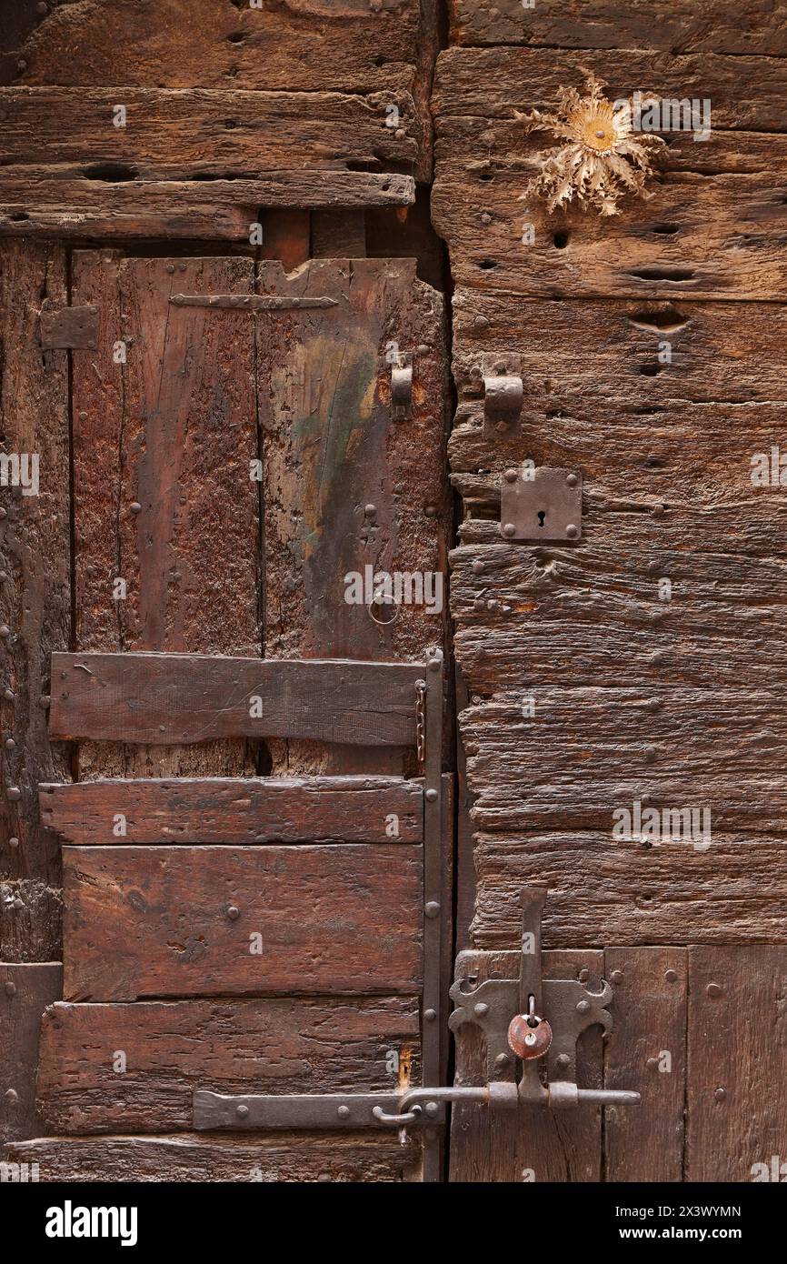 Antike rustikale Holztür. Außenbereich mit Schotterstruktur. Spanien Stockfoto