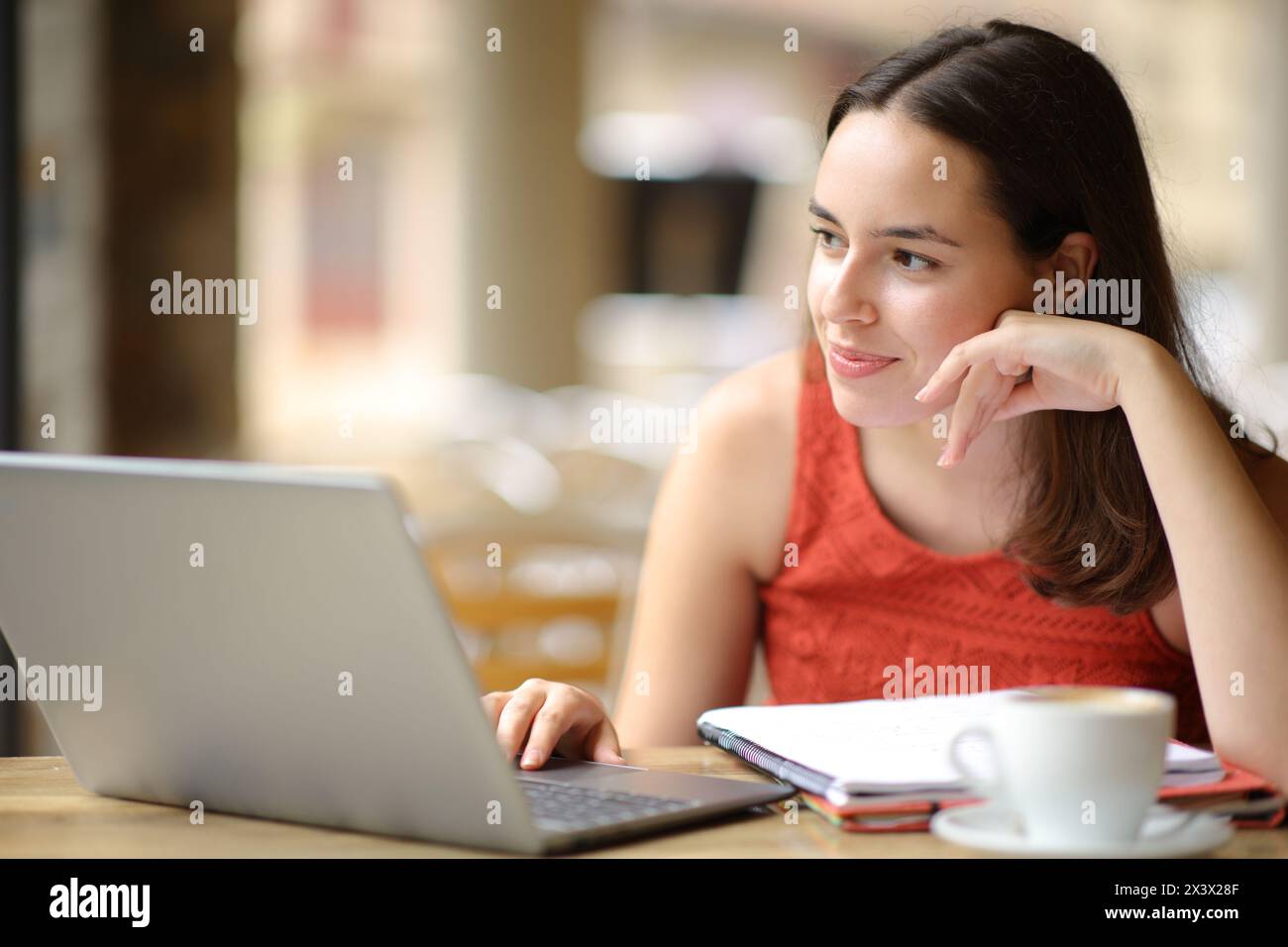 Zufriedenes E-Learning für Schüler, die auf einer Restaurantterrasse wegschauen Stockfoto