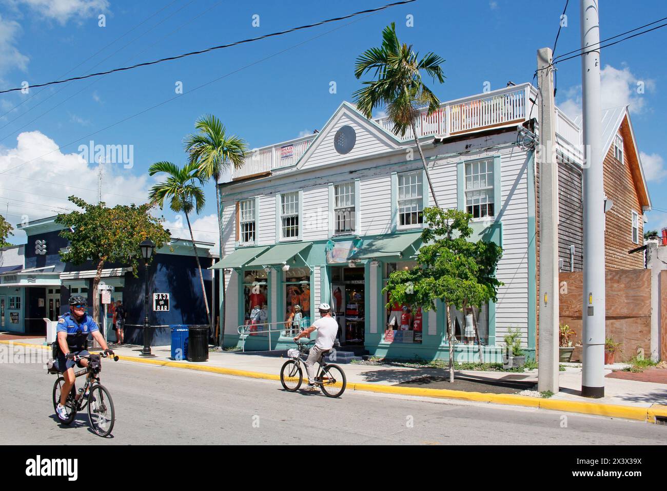 USA. Florida. Die Tasten. Key West. Historisches und touristisches Zentrum. Touristen- und Polizeibeamter, der Fahrrad fährt. Stockfoto