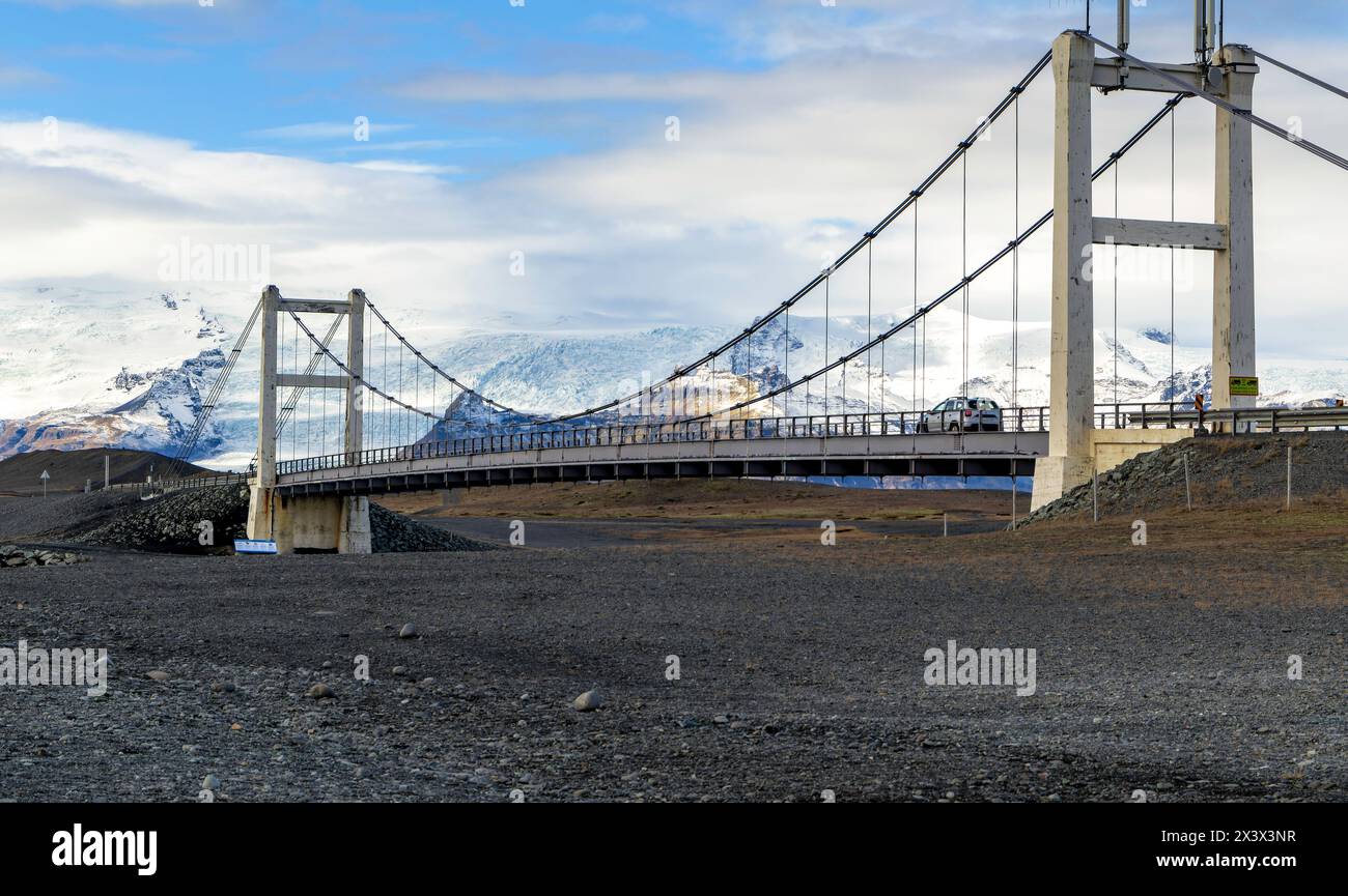 Eine Brücke über einen schneebedeckten Berg mit einem Auto, das über ihn fährt. Die Brücke ist lang und erstreckt sich über ein Tal Stockfoto