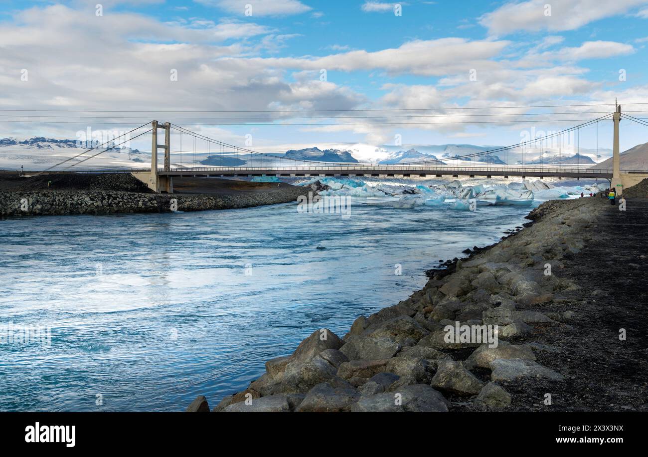 Eine Brücke überspannt einen Fluss mit Blick auf Eis und Schnee. Die Brücke hängt über dem Wasser und der Himmel ist klar Stockfoto