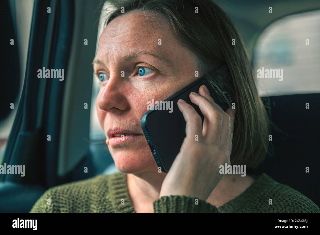 Porträt einer ernsten, unglücklichen erwachsenen Frau während eines Telefongesprächs auf der Rückbank des Autos, selektiver Fokus Stockfoto