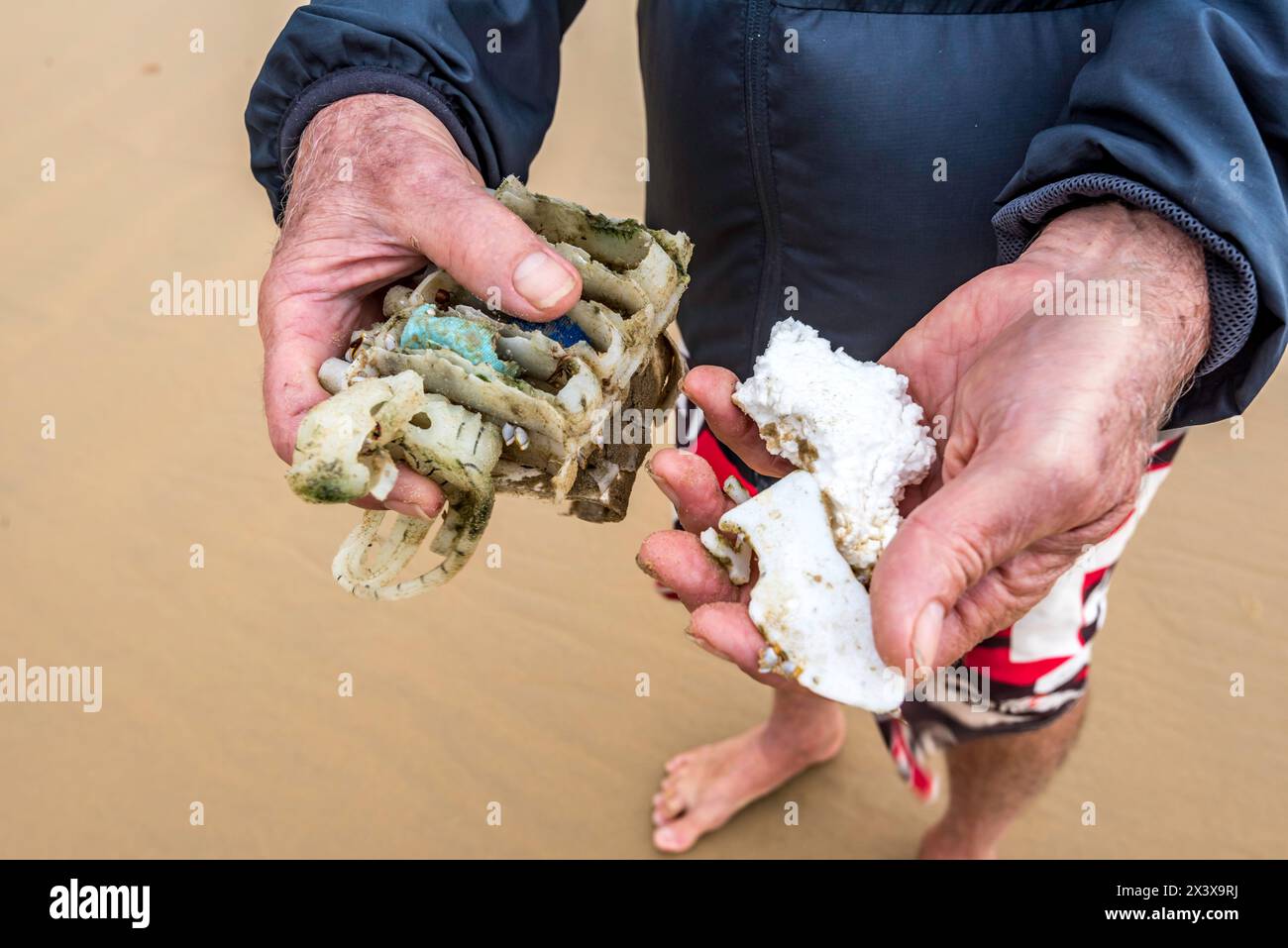 Eine Nahaufnahme der Hände eines älteren Mannes mit Styroporteilen und Hartplastik, die am Mission Beach in Queensland gesammelt wurden, bei einem regelmäßigen Morgenspaziergang Stockfoto