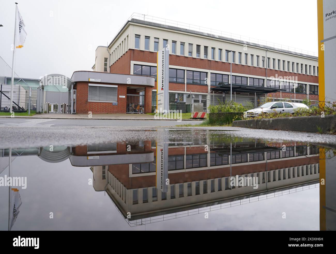 Norderstedt, Deutschland. April 2024. Ein Fabrikgebäude der Jungheinrich AG spiegelt sich in einer Pfütze wider. Jungheinrich ist ein Hersteller von Gabelstaplern und Palettenhubwagen. Quelle: Marcus Brandt/dpa/Alamy Live News Stockfoto
