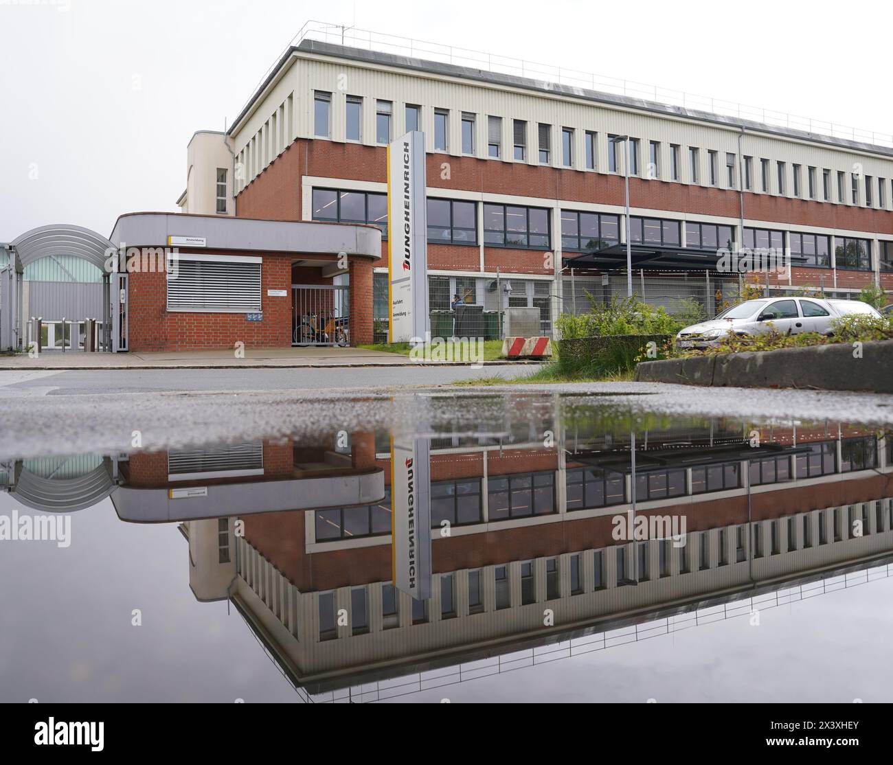 Norderstedt, Deutschland. April 2024. Ein Fabrikgebäude der Jungheinrich AG spiegelt sich in einer Pfütze wider. Jungheinrich ist ein Hersteller von Gabelstaplern und Palettenhubwagen. Quelle: Marcus Brandt/dpa/Alamy Live News Stockfoto