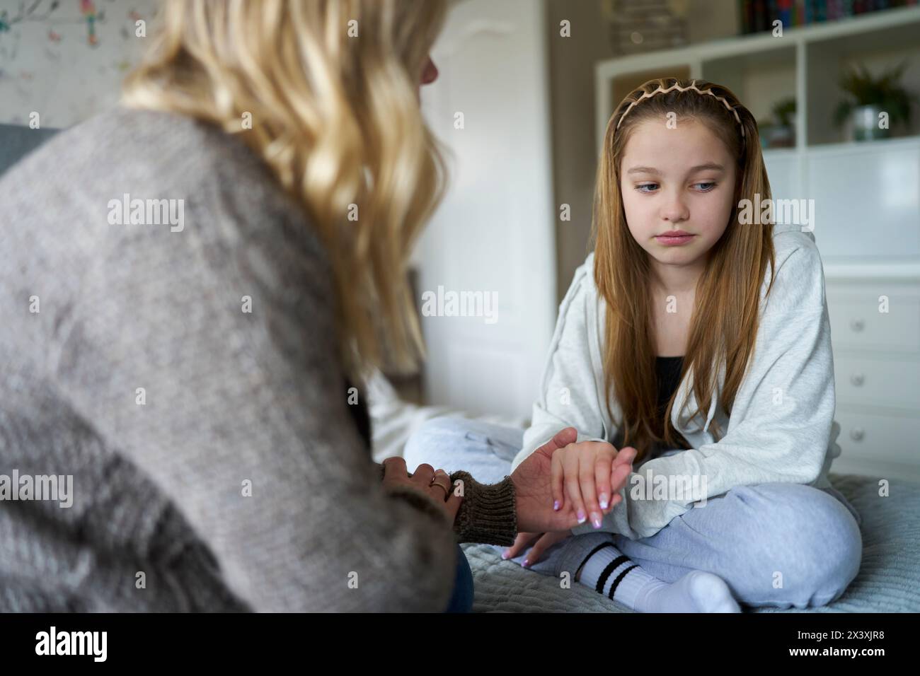 Reife Mutter Sitzt Auf Bett Mit Unglücklicher Teenager-Tochter Zu Hause Doscussing Problem Stockfoto