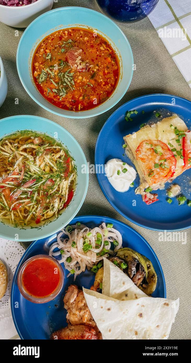 Auswahl an Speisen auf rustikalem Tisch mit Sushi, Salat, Suppe, Fleisch. Wunderschön präsentiert und lecker. Stockfoto
