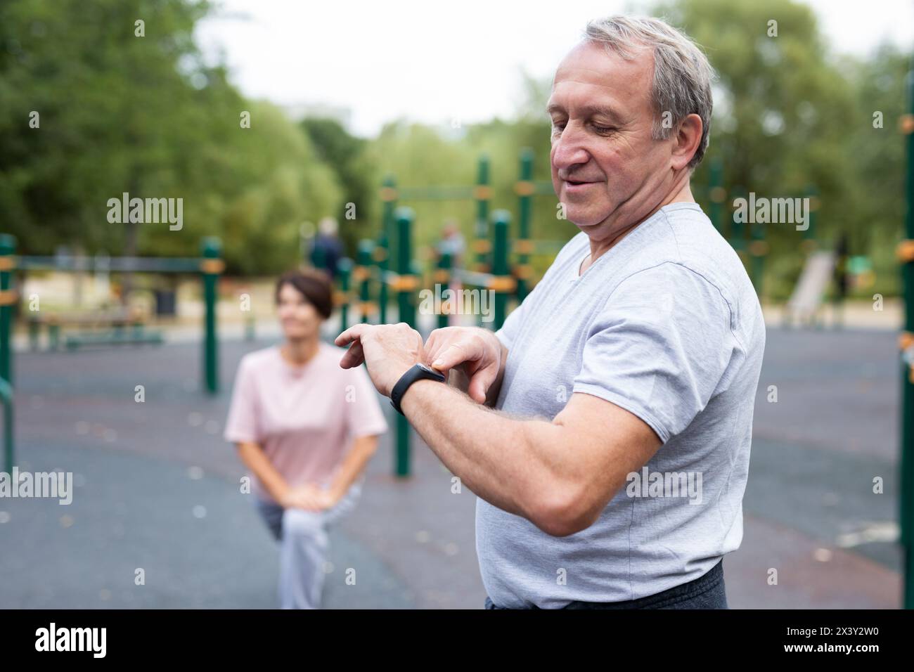 Ein erfahrener Sportler schaut beim Sport im Stadtpark auf die Fitnessuhr oder auf einen Schrittzähler Stockfoto