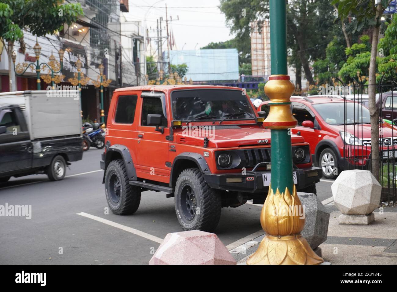 Ein Jeep parkt am Rande einer befahrenen Straße in Indonesien Stockfoto