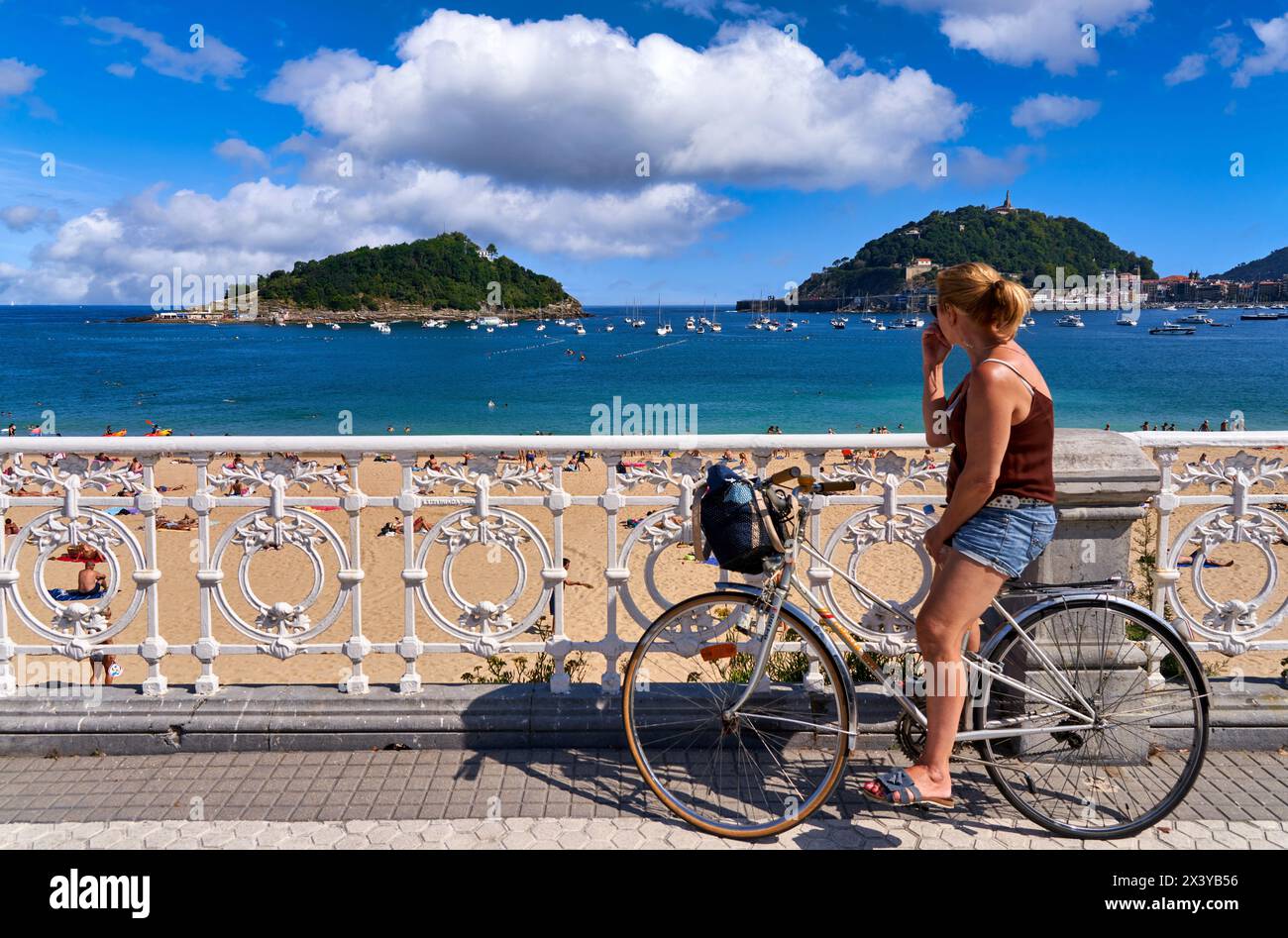 Fahrradtouristen am Ondarreta Beach, hinter Santa Clara Island und Mount Urgull, Donostia, San Sebastian, kosmopolitische Stadt mit 187.000 Einwohnern, nicht Stockfoto