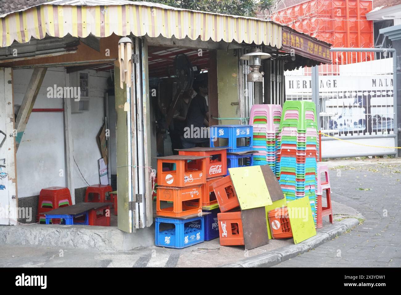 Stapel leerer Getränkeflaschenkisten und Stapel kurzer Plastikstühle in einem alten Laden am Straßenrand Stockfoto