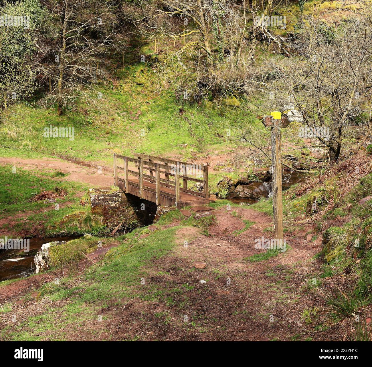 Bergbach bei Abercynafon in den Brecon Beacons, Powys, Wales mit hölzernem Fußgängersteg und Wegweiser Stockfoto