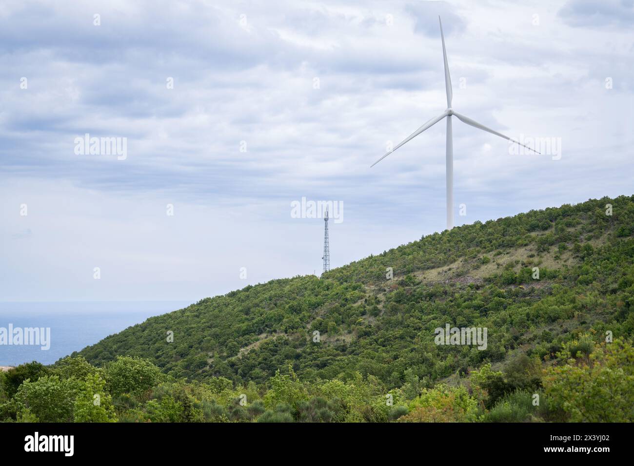 Windkraftanlage auf der Spitze des Berges mit Meer im Hintergrund. Stockfoto