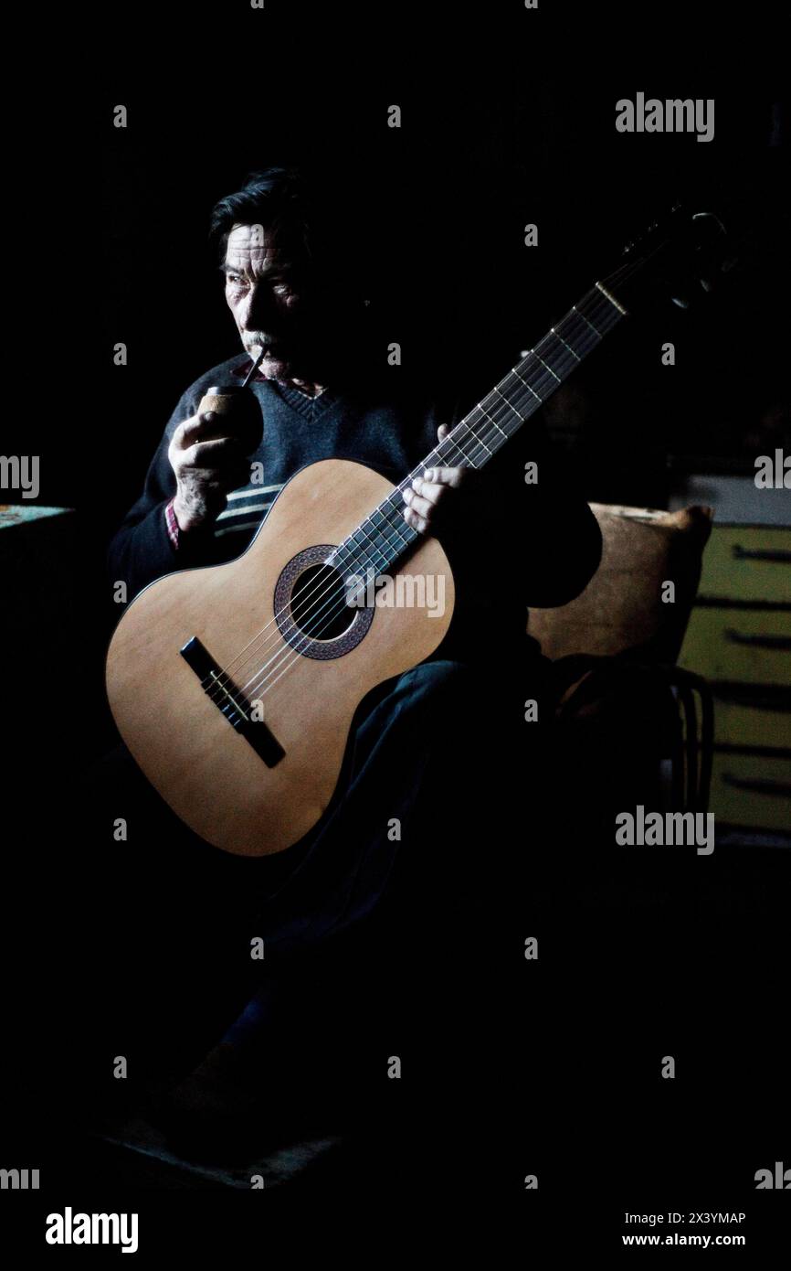 Gaucho schlürft an Mate, während er Gitarre in Patagonien Argentinien spielt Stockfoto