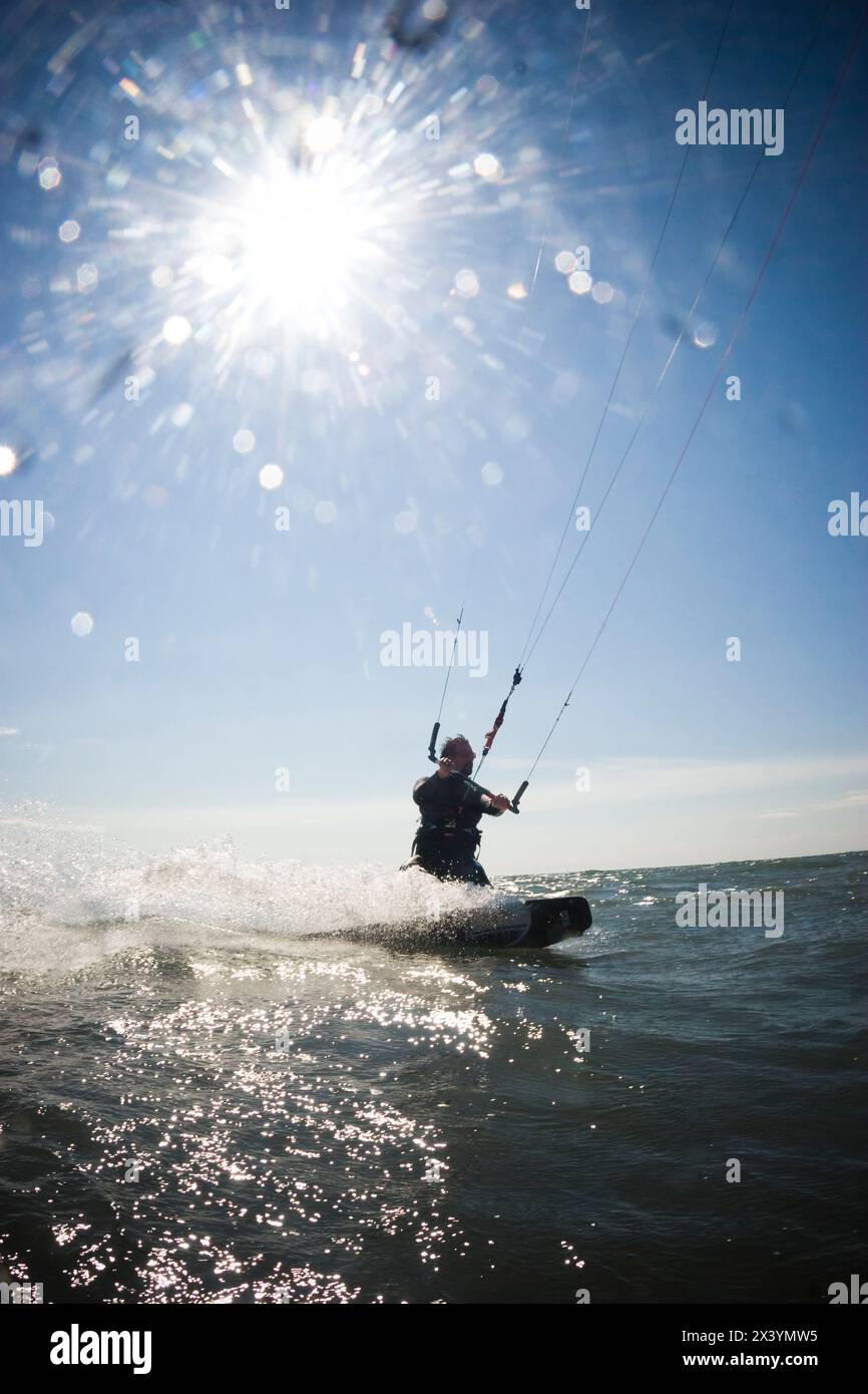 Ein mittelgroßer Mann reitet auf dem Meer, während er in Homer, Alaska, Kitesurfing. Stockfoto