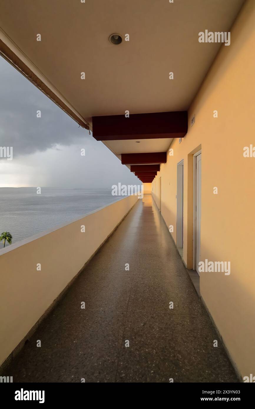 207 die offene Galerie führt zu den Zimmern im Jagua Hotel, mit Blick auf den stürmischen Himmel über Jagua Bay nach starkem tropischem Regen. Cienfuegos-Kuba. Stockfoto