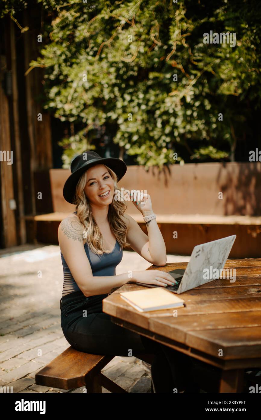 Lächelnder tätowierter Freelancer, der stilvoll im Freien arbeitet Stockfoto